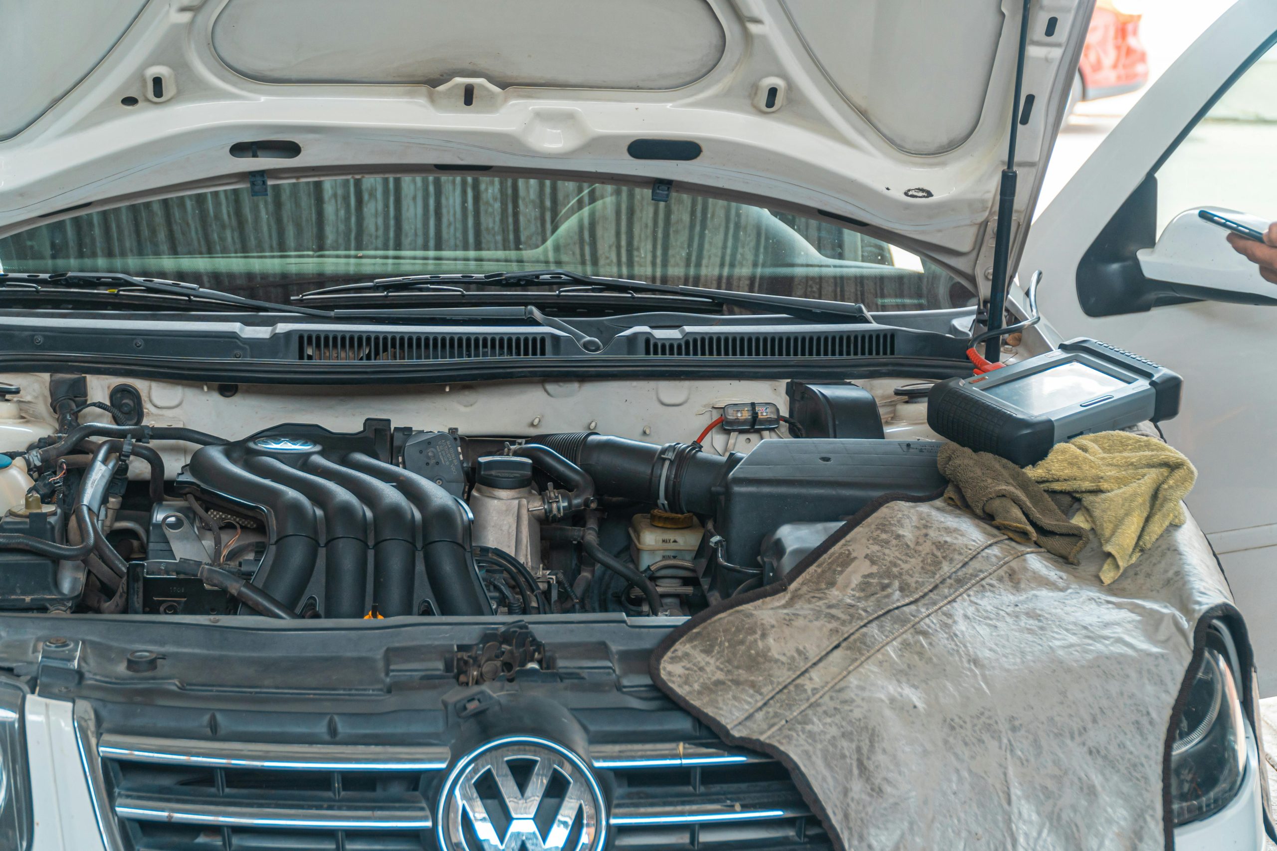 Close-up of a Volkswagen car engine undergoing repair in a garage, tools and diagnostic equipment in use.